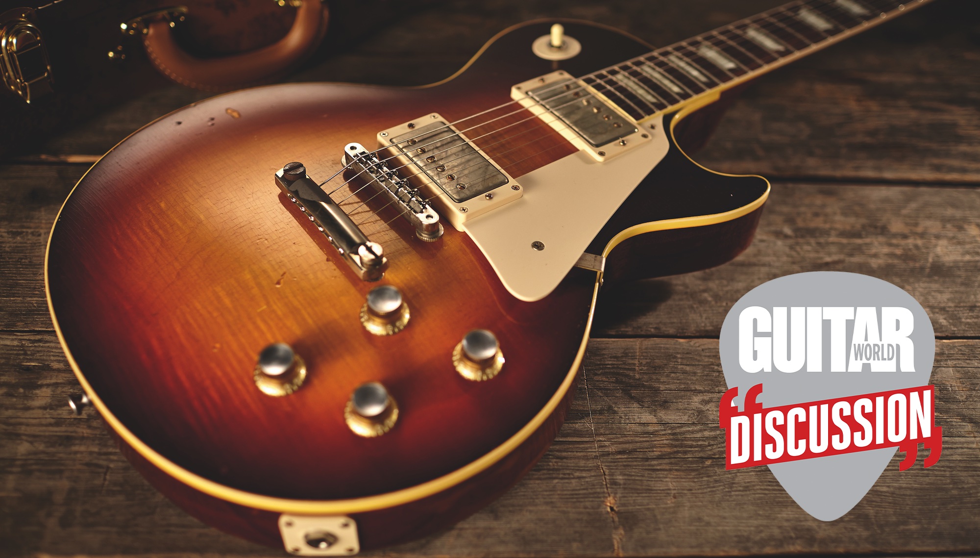 A Gibson Les Paul, laid down on a hardwood floor, with its case in the background