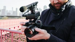 Man holding a Panasonic Lumix GH5 II, one of the best best hybrid cameras