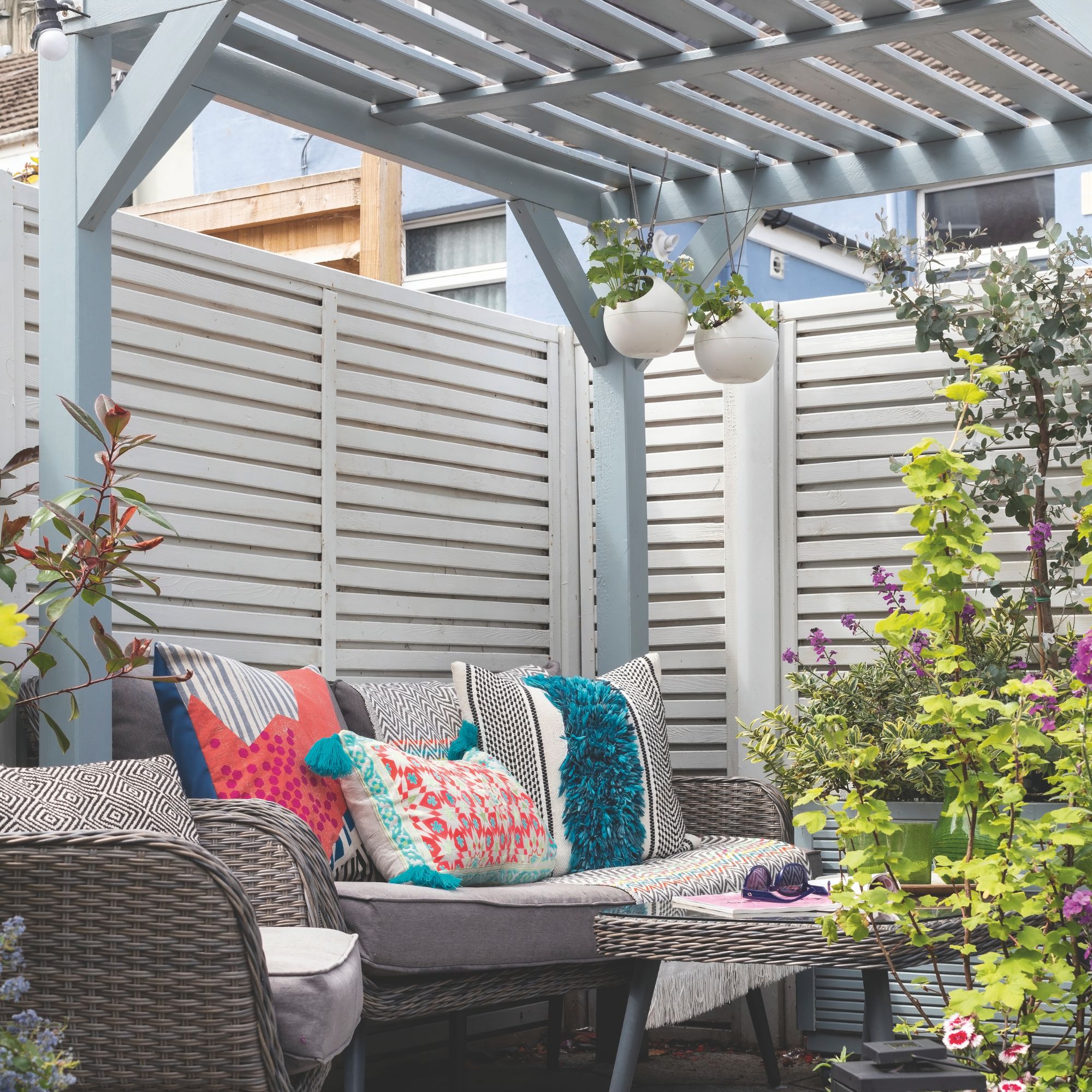 Duck egg blue pergola over rattan garden furniture with colourful cushions