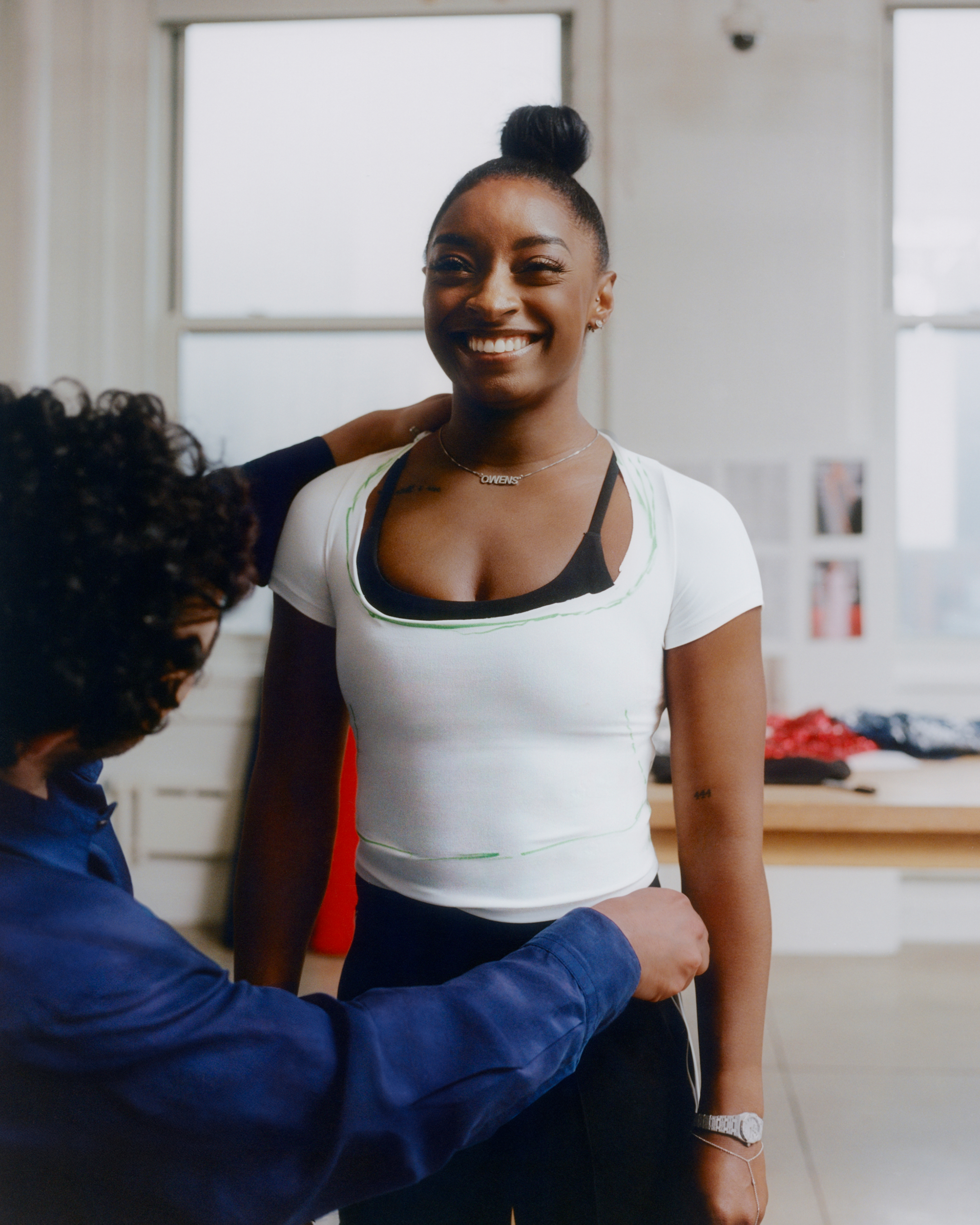 Simone Biles smiles at the camera as Zac Posen measures her for her gown