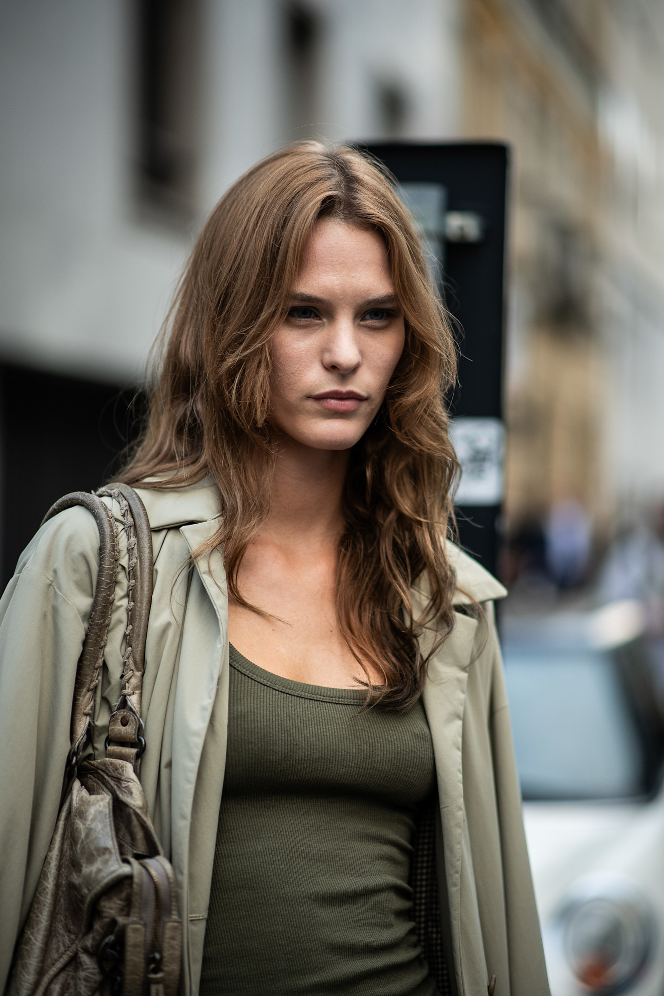 a woman with light brown hair wearing a light green shirt over a dark green tank top