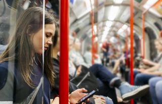 What is a hypochondriac? UK, London, young woman in underground train looking at cell phone