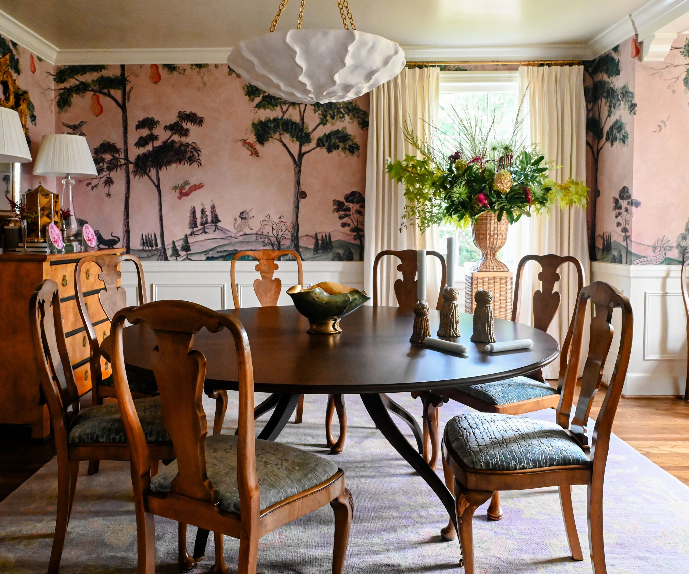 A dining room with pink wallpaper and traditional decor.