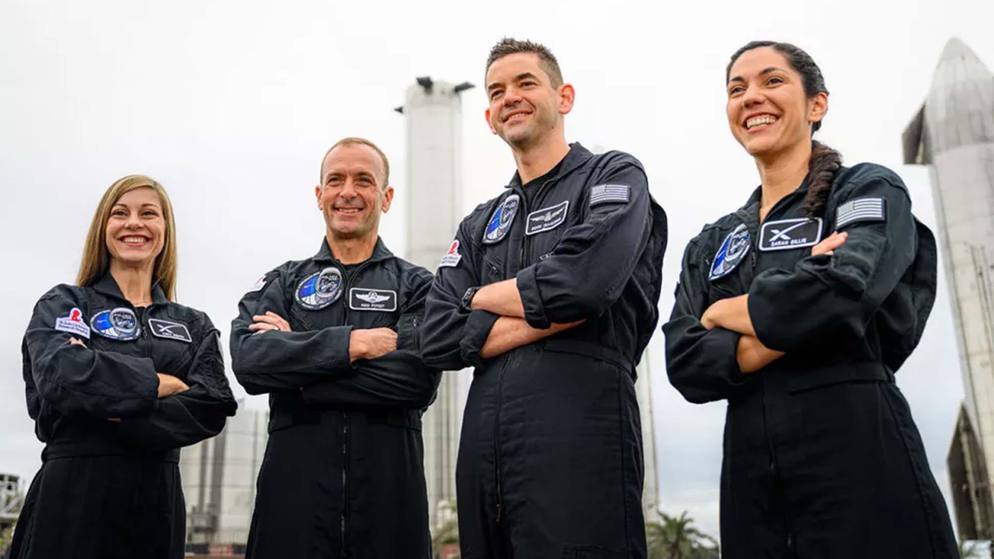 The crew of the Polaris Dawn mission standing in front of SpaceX Dragon rockets