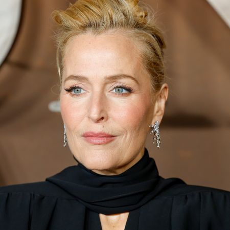a close up paparazzi photo of a woman posing on a red carpet in front of a brown backdrop