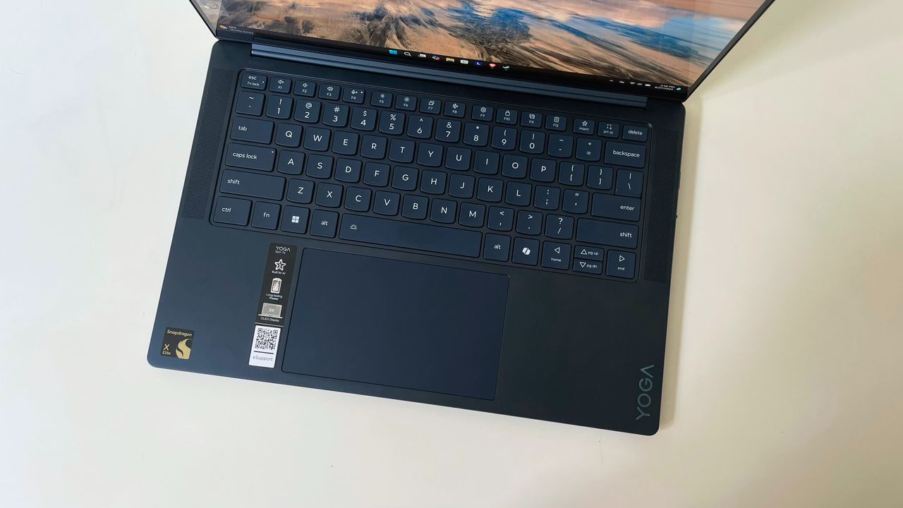 A downward view of a black laptop's keyboard and trackpad, sitting on a white surface.