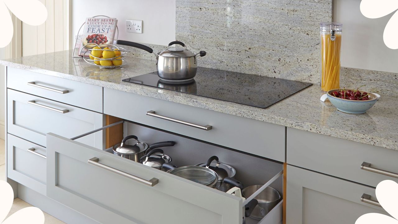 Black induction stove with control panel near marble countertop in pale grey kitchen with a stainless steel saucepan and products on cooking surface. Cookery and homemade food concept to show how we test induction pans