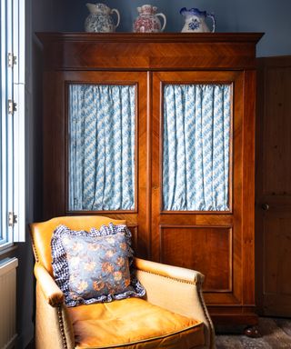 antique cupboard with fabric lined glass doors and old leather tub chair