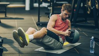 Man performs Russian twist exercise using a medicine ball