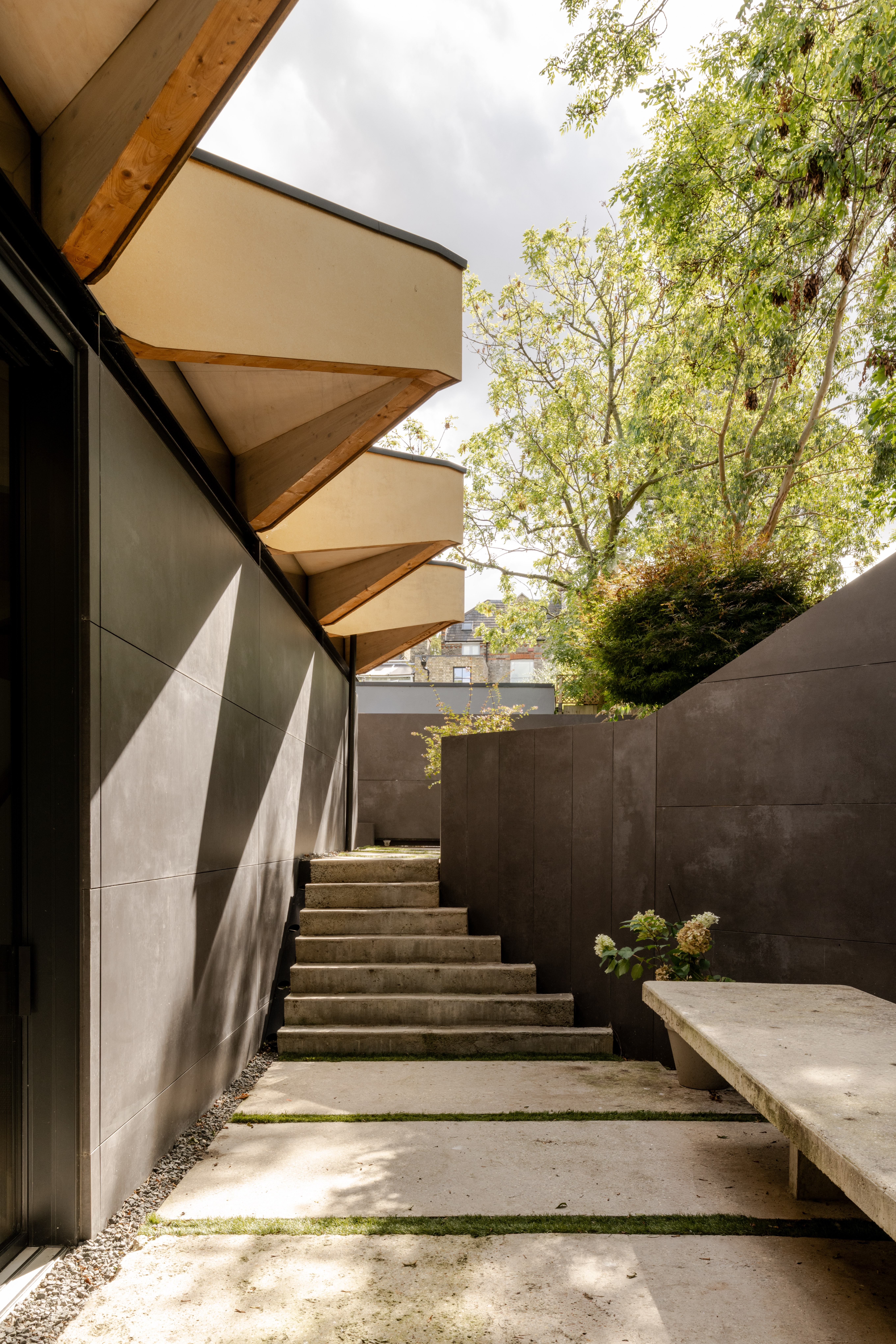 arbour house, a low, one storey home in a back year among trees, but with a distinctive angular roof