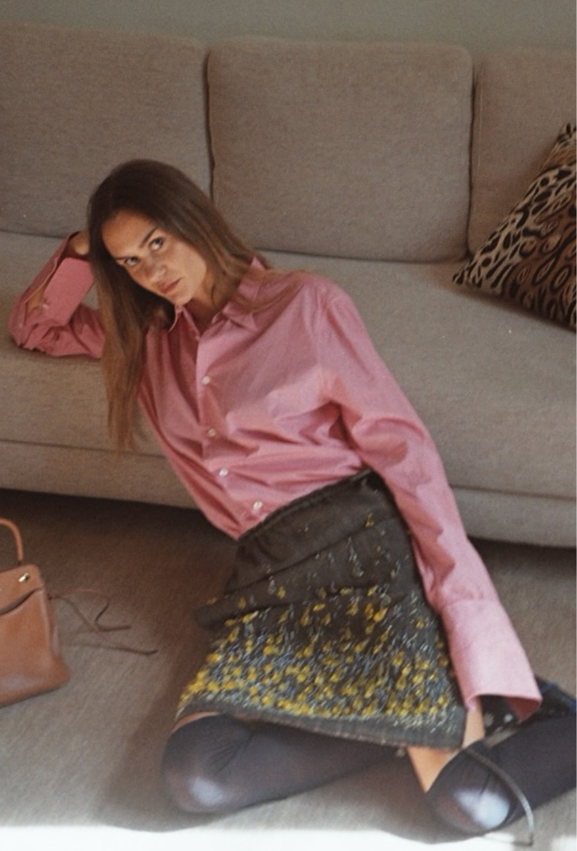 An image of @annelauremais wearing a printed Prada skirt with knee-high socks and a pink shirt.