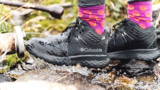 Hiker's feet wearing the Columbia Konos TRS outdry Mid Hiking Shoe in a stream