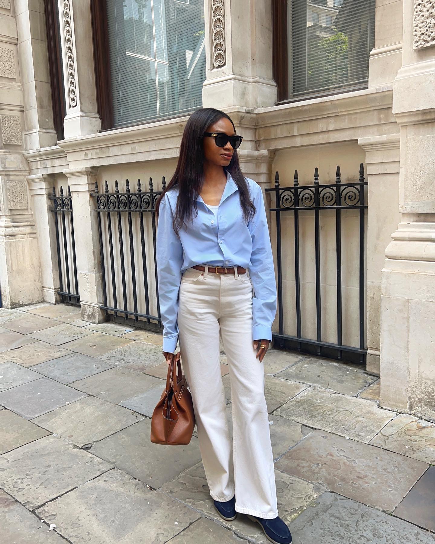 Influencer styles a blue shirt with cream trousers.