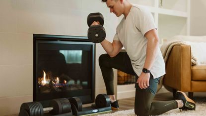 Young fit men working out with dumbbells in front of an electric fireplace