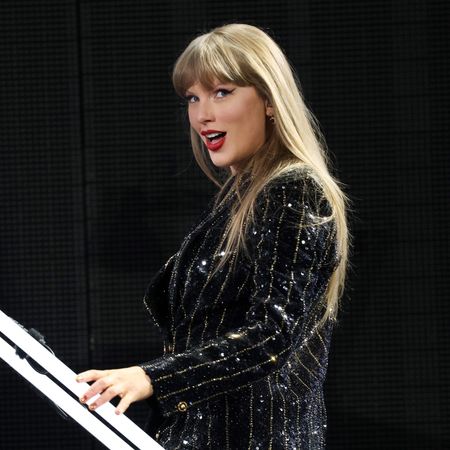 Taylor Swift performs onstage during the Eras Tour wearing a black beaded versace blazer with her signature red lipstick by Pat McGrath