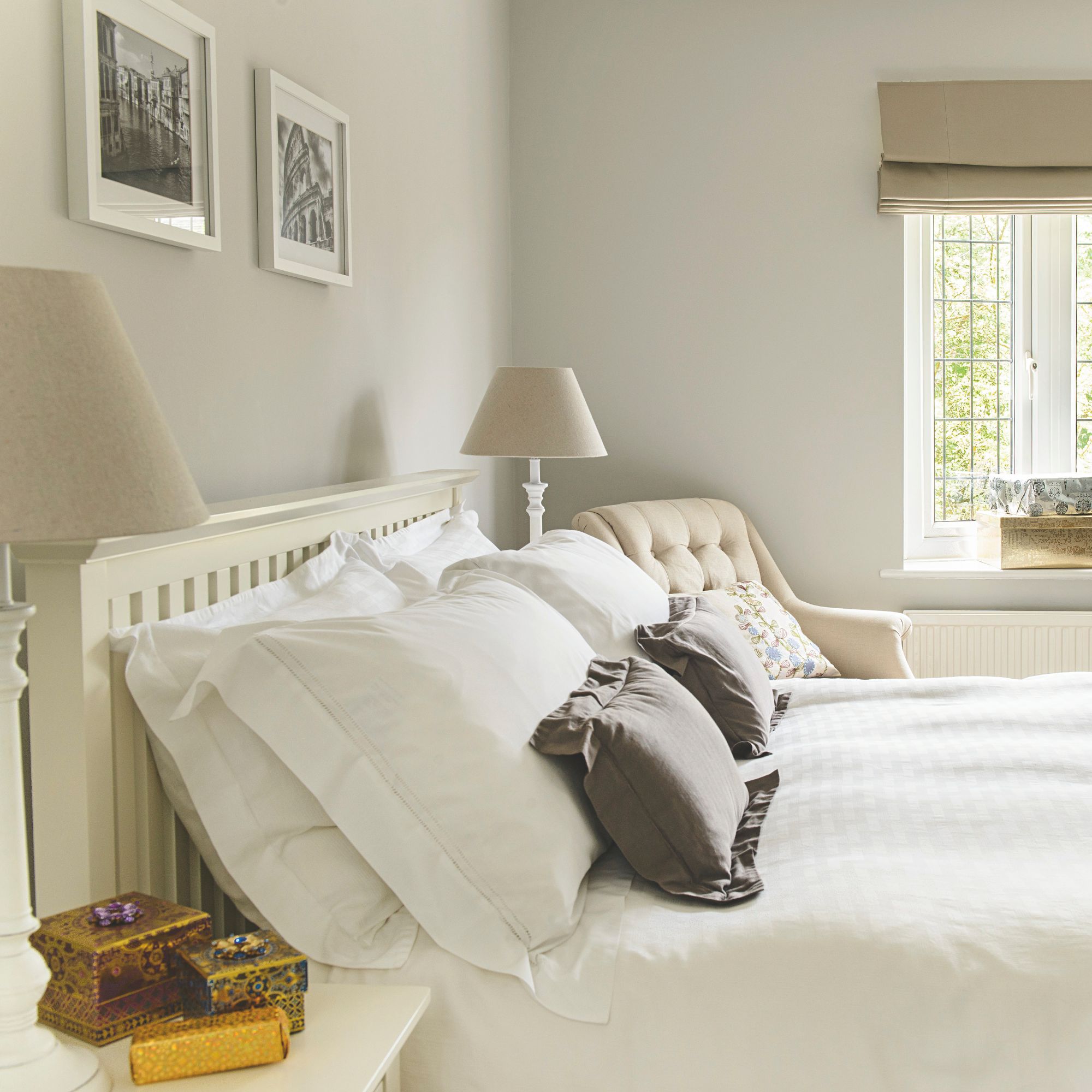 A neutral bedroom with beige walls, a white bed and grey cushions