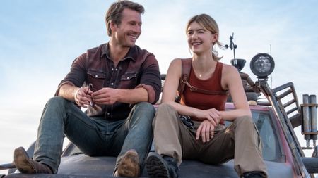 Daisy Edgar-Jones and Glen Powell sitting on the hood of a truck and smiling in Twisters