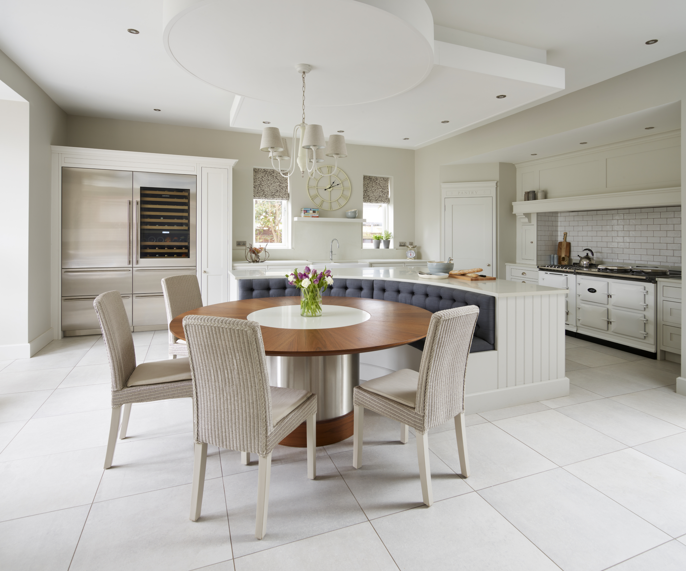 large white kitchen with blue upholstered seating area integrated with kitchen island