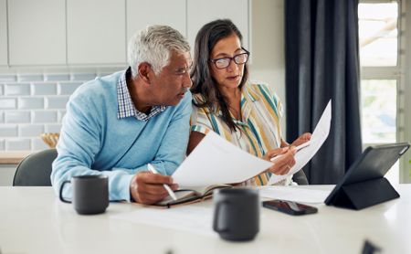 A senior couple reviews finances at the kitchen table.