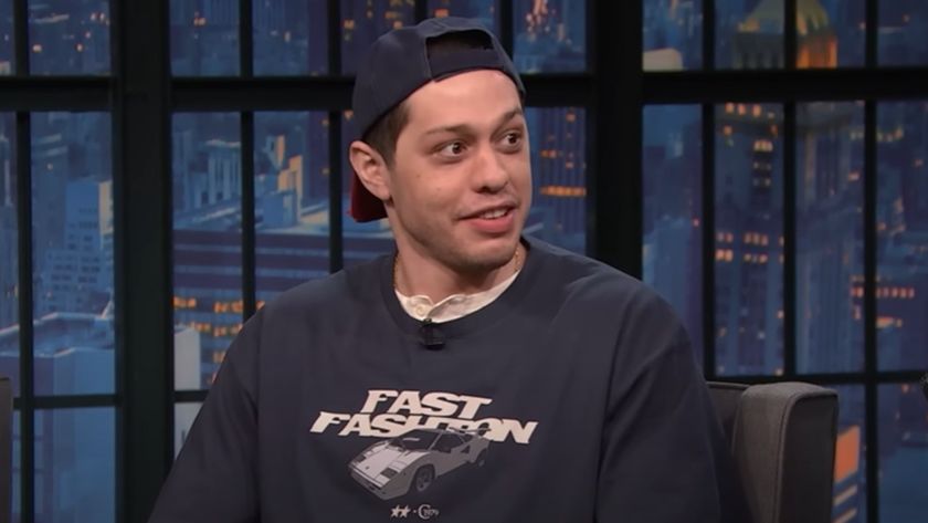Pete Davidson looking curiously to his right while on Late Night with Seth Meyers. 
