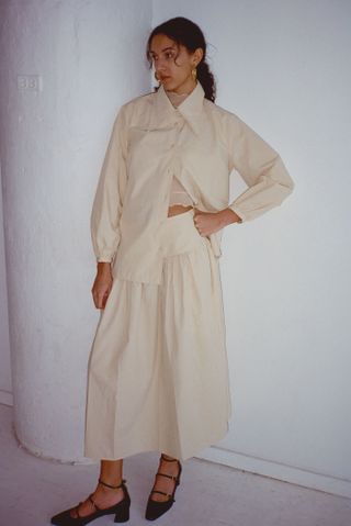model wears lulu skirt in cream and white button down 