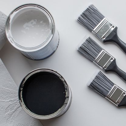 Paint brushes laying on side next to paint pots