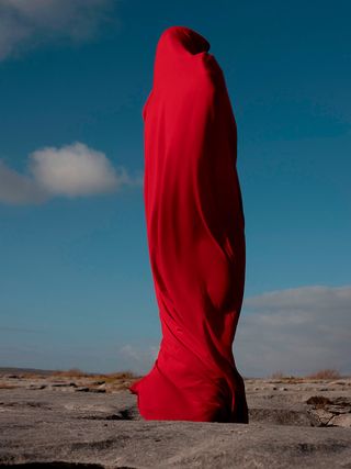 Figure wrapped in red cloth in desert
