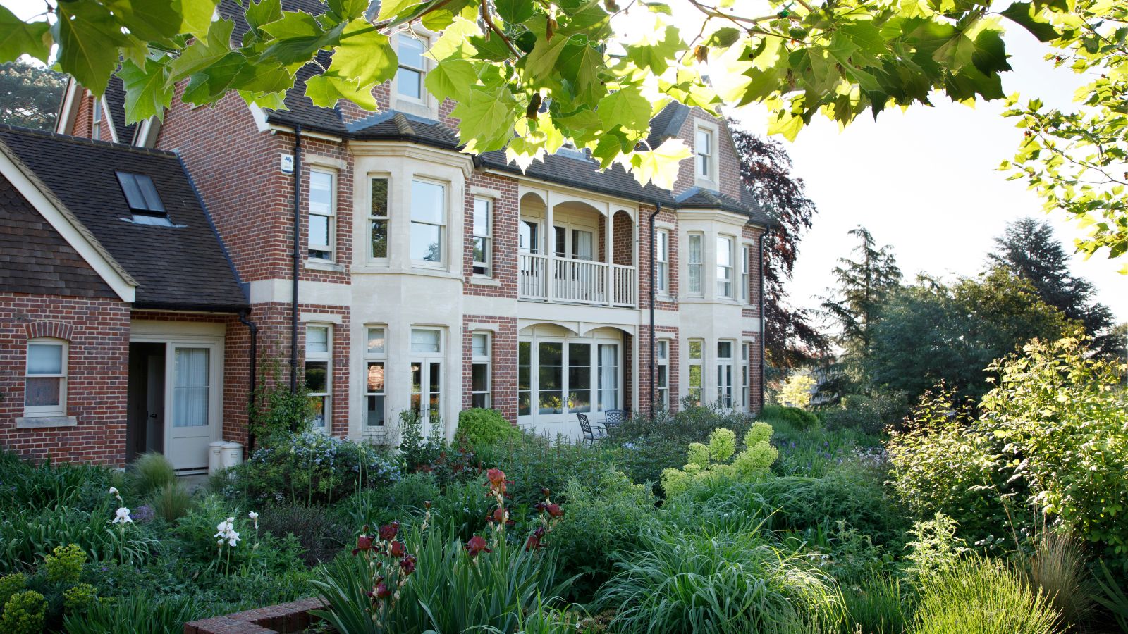 Red brick house with balcony, cream painted windows and large garden