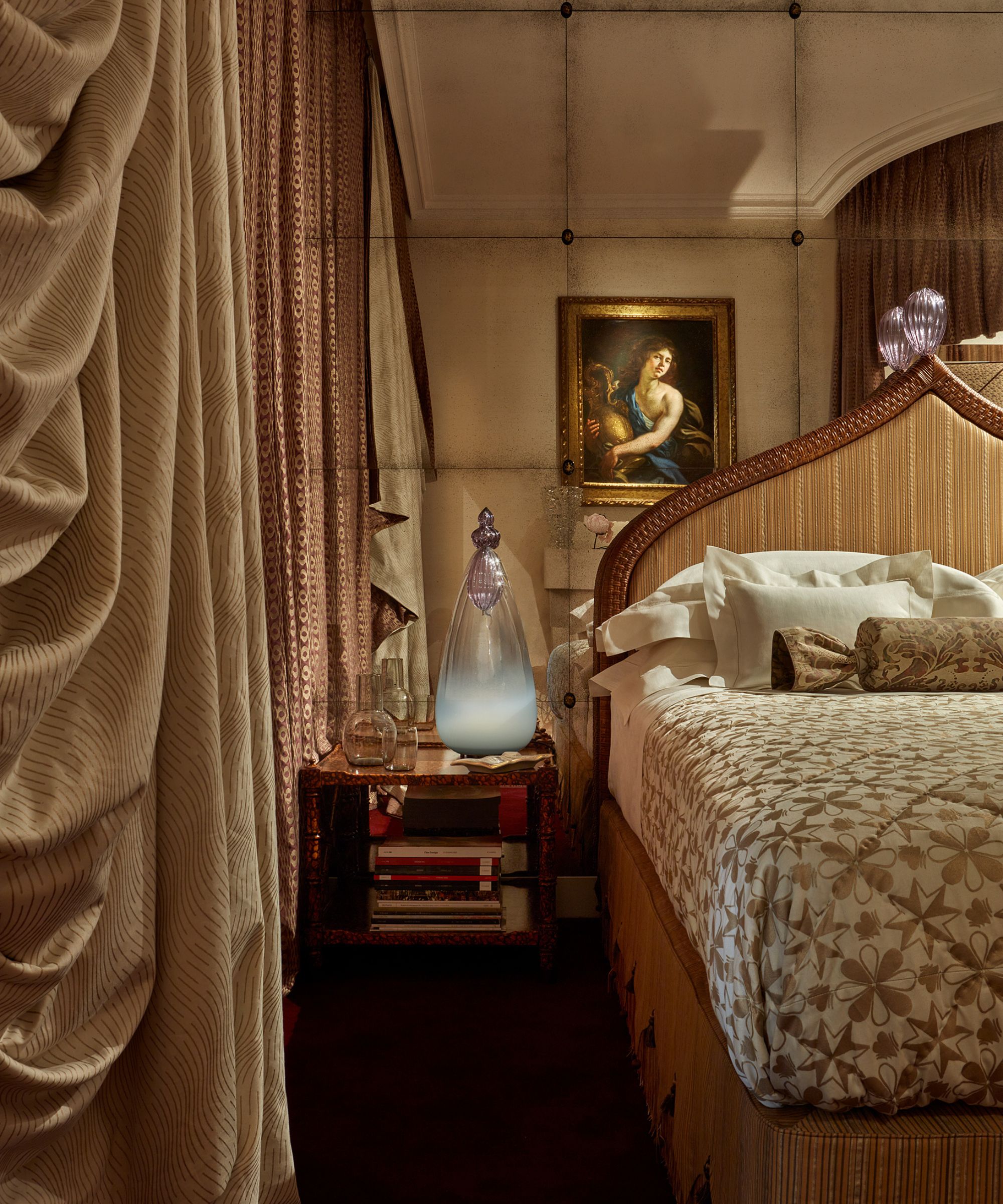 A bedroom with ruched heavy drapes, a large ornate bed with a gold headboard and quilt.