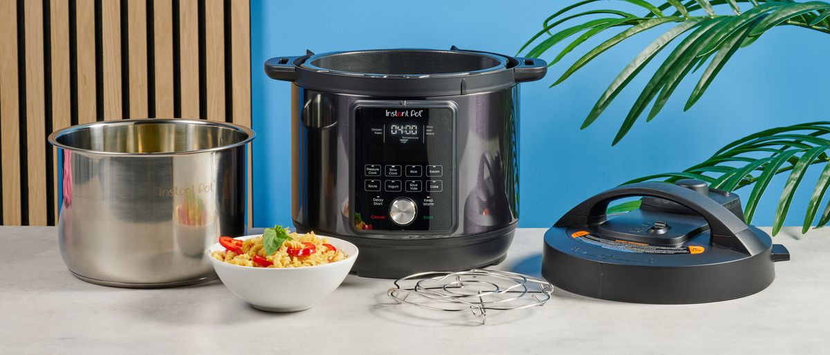 a black instant pot with a dial and touchpad is photographed against a blue background