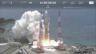 a yellow rocket launches from a seaside pad