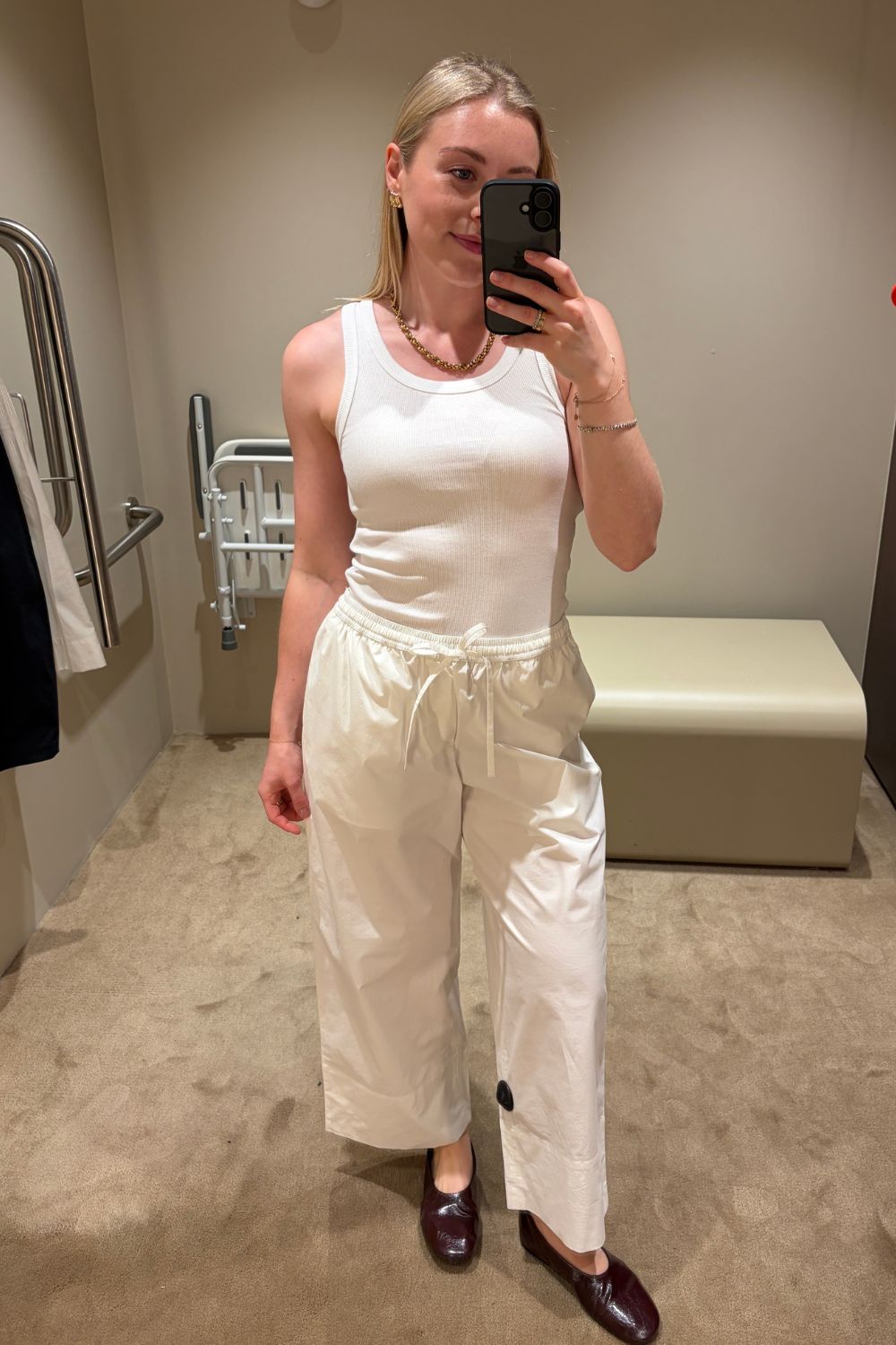 Woman wears white tank top, white cotton trousers and ballet flats