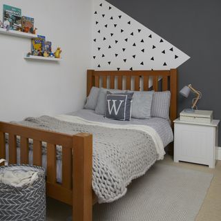 Grey and white color blocking wall art with a wooden bed and grey bedding with a wool bed-throw