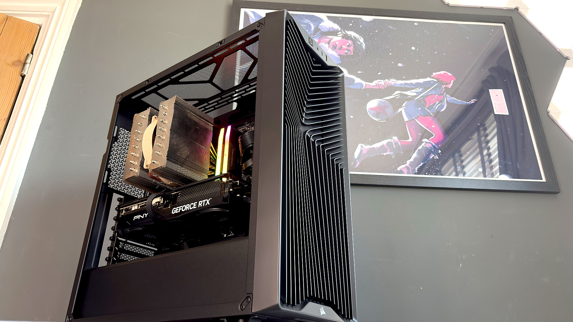 A Corsair PC case, the 3200D, on a desk with various panels removed and ready for a PC build.