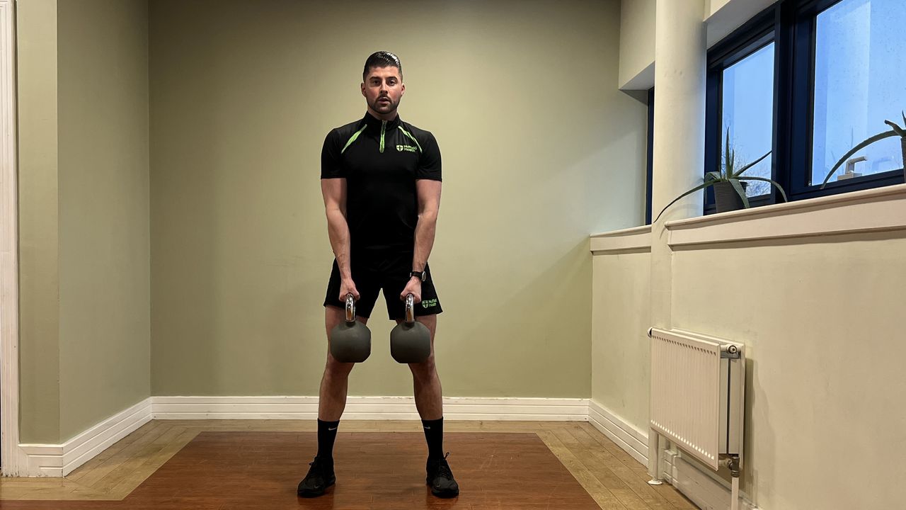 Sam Quinn, a strength coach from Nuffield Health, demonstrates a kettlebell shoulder press