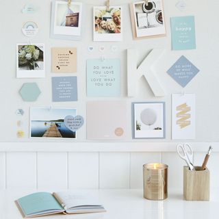 white wall with photos and candle on white table