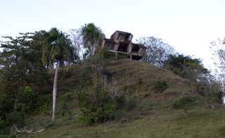 Abandoned concrete building on top of hill in forest