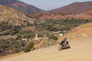 Image shows Anna riding up the Tizi n'Telouet gravel pass in Morocco