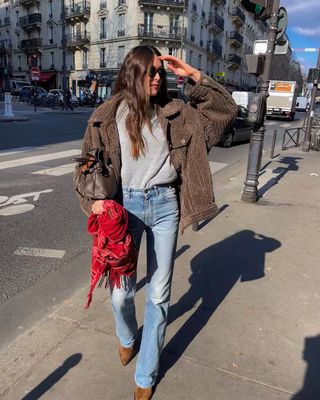 French woman wearing Western boots with jeans and brown jacket.