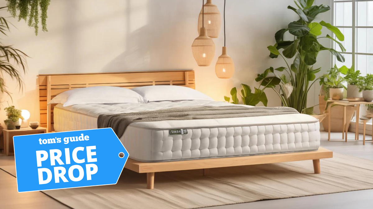 A simba mattress on a wooden bed frame in a clean and tidy bedroom with a price drop label over the top of the image