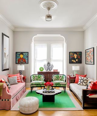 living room with pink sofa, white sofa, green and white patterned chairs, and bold green rug
