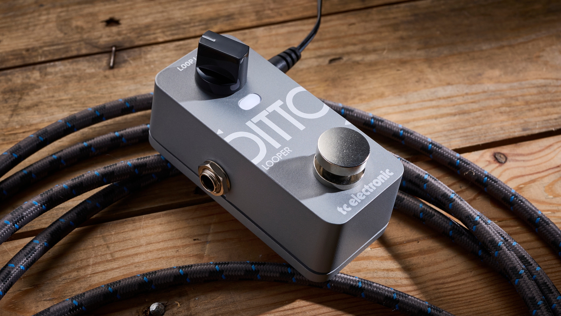 A TC Electronic Ditto 2 looper pedal on a wooden floor with a guitar cable