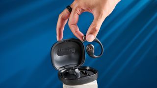 Jlab epic open sport open-earbuds in a black colorway photographed on a blue background.