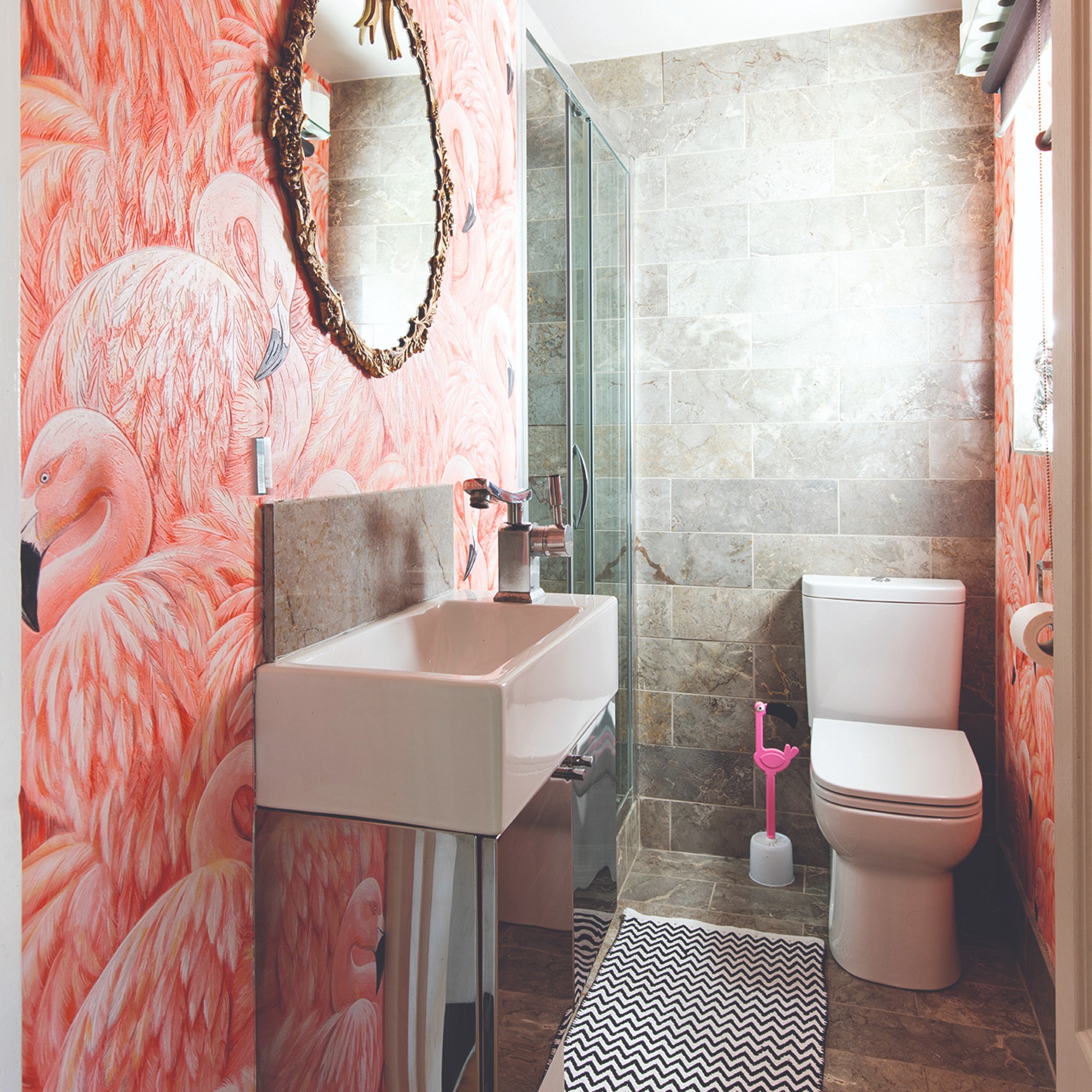 A small bathroom with a toilet covered in a flamingo wallpaper