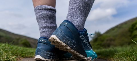 The back of a pair of feet and lower legs, wearing hiking shoes and a pair of BAM Twist Walking Socks.