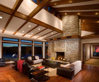 Large open plan living room with stone fireplace, plush sofas and fitted ceiling light fixtures