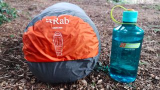 Rab Andes Infinium 800 Sleeping Bag in stuff sack beside Nalgene water bottle