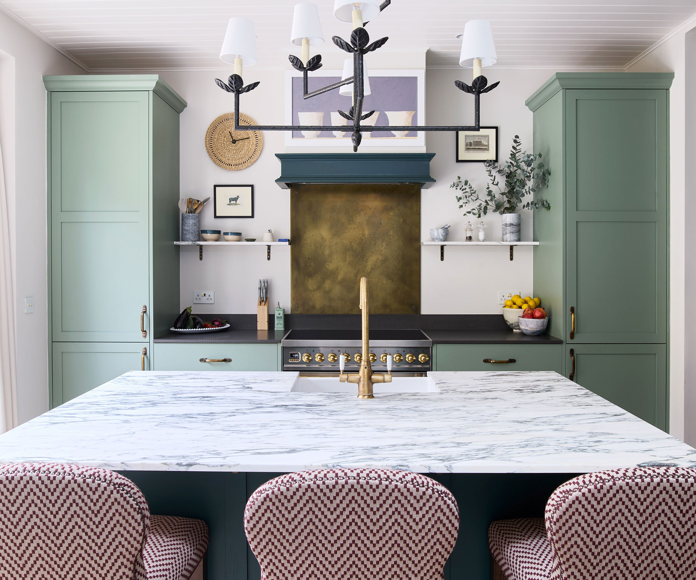 small green kitchen with square island unit with marble work surface and brass kitchen tap