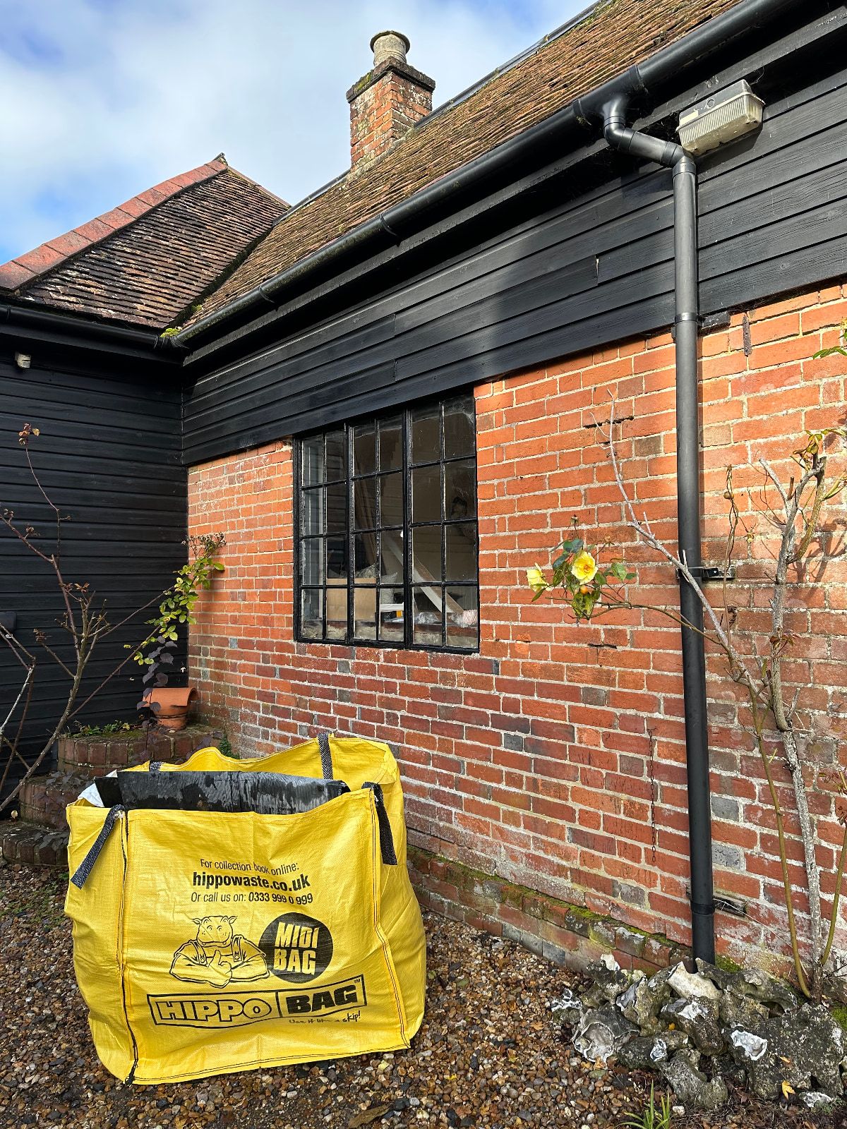 A yellow bag of DIY supplies outside a redbrick home