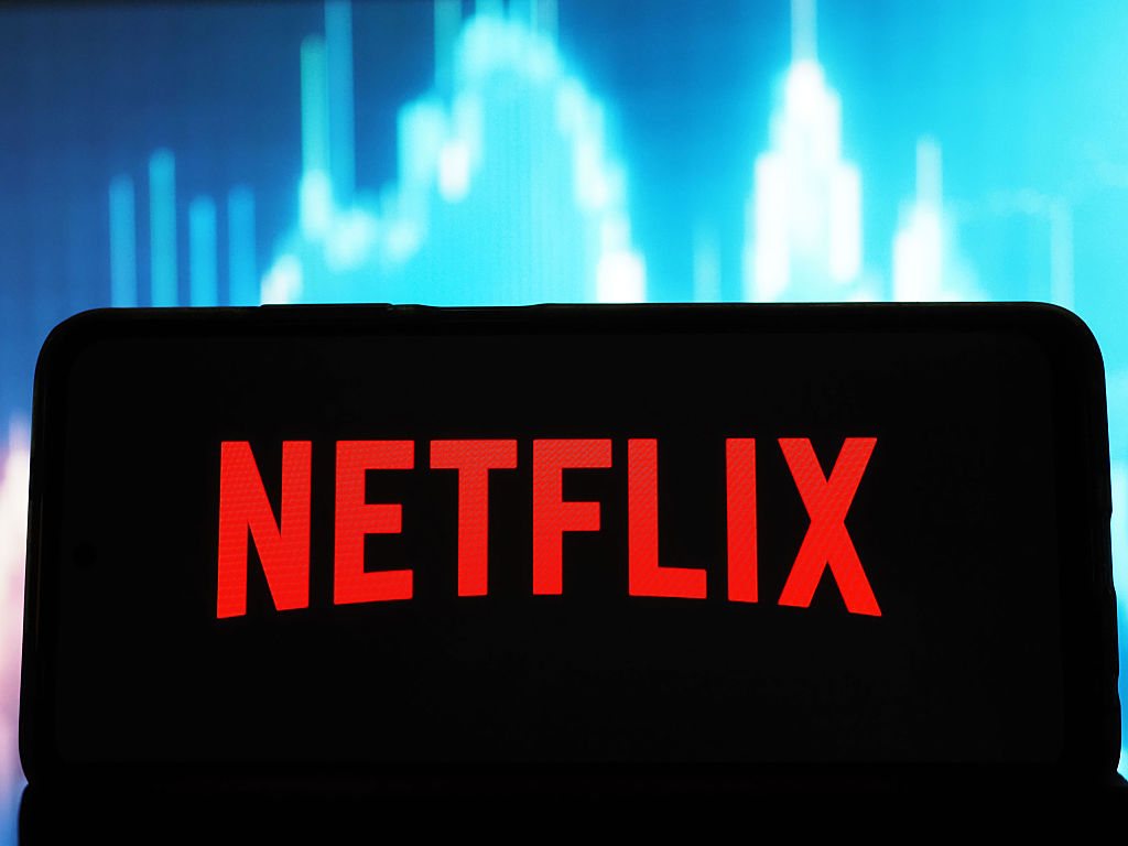 Netflix, Inc. logo seen displayed on a smartphone with share price chart in the background